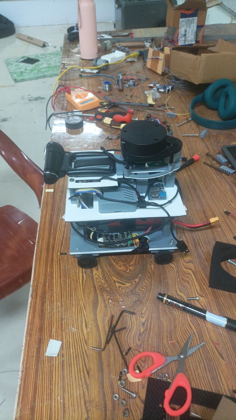 The robot on a cluttered workbench mid-build, surrounded by tools and wiring.